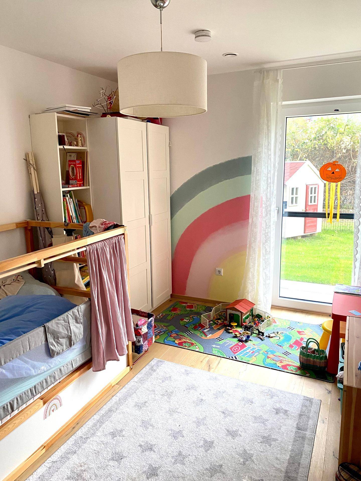 Kinderzimmer mit Etagenbett, farbenfroher Wandgestaltung und Zugang zum Garten.