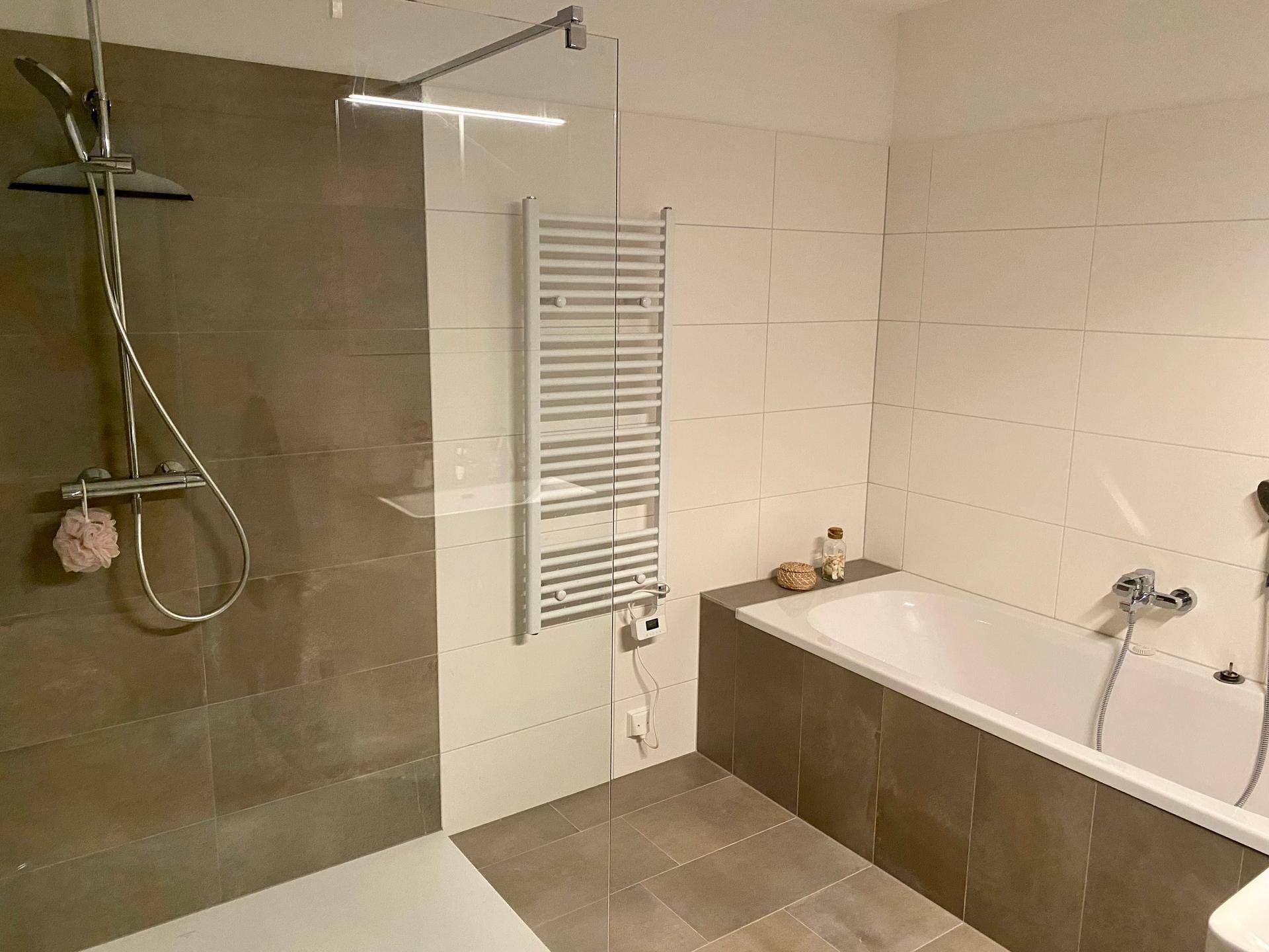 Modernes Badezimmer mit Badewanne, begehbarer Dusche und beheiztem Handtuchhalter.