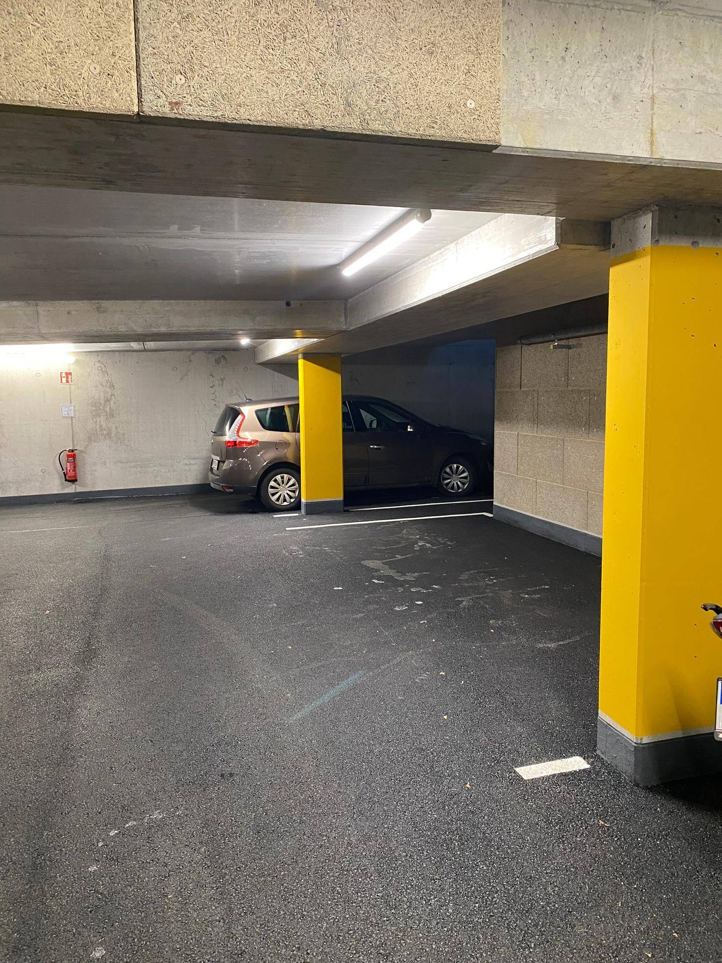 Tiefgarage mit markierten Stellplätzen und gelben Säulen.