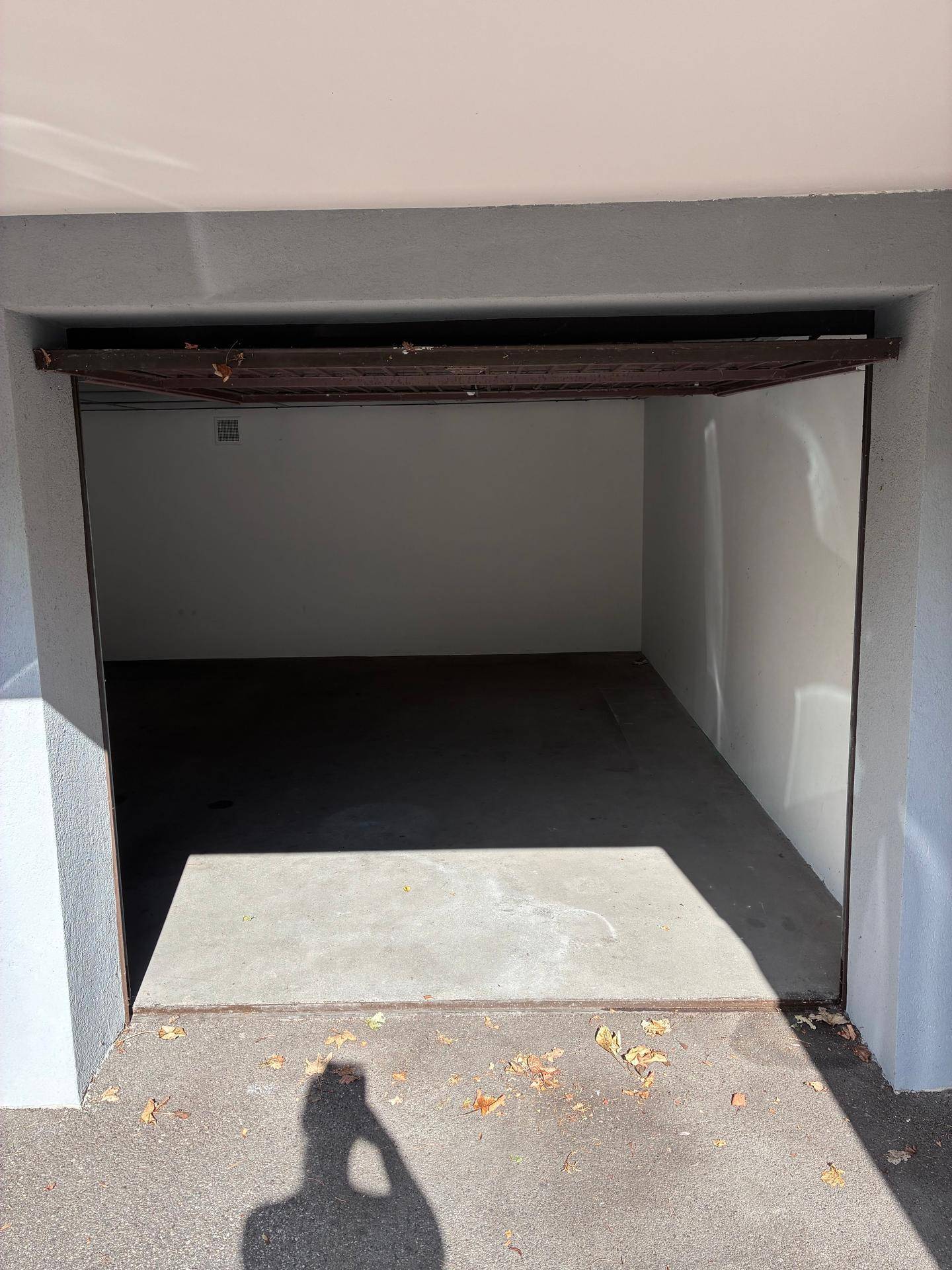 Offenes Garagentor gibt den Blick auf den leeren, sauberen Innenraum mit Betonboden frei.