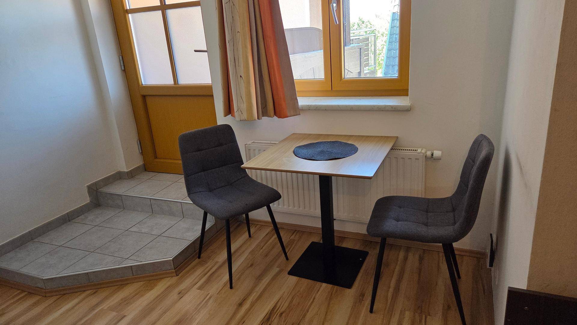 Kleiner Essbereich mit Tisch und Stühlen, angrenzend an einen Eingangsbereich.