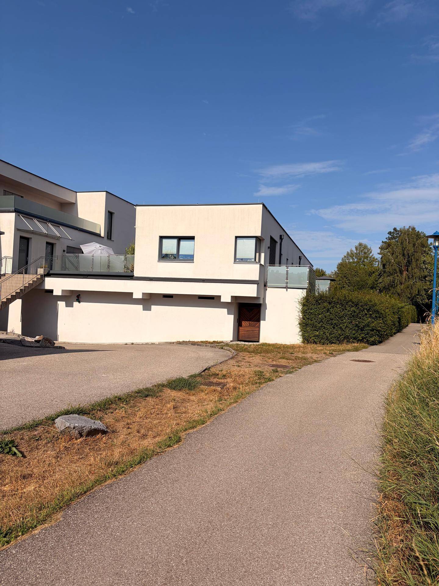 Moderne Wohnanlage mit weißer Fassade, großen Fenstern und gepflegter Außenanlage.