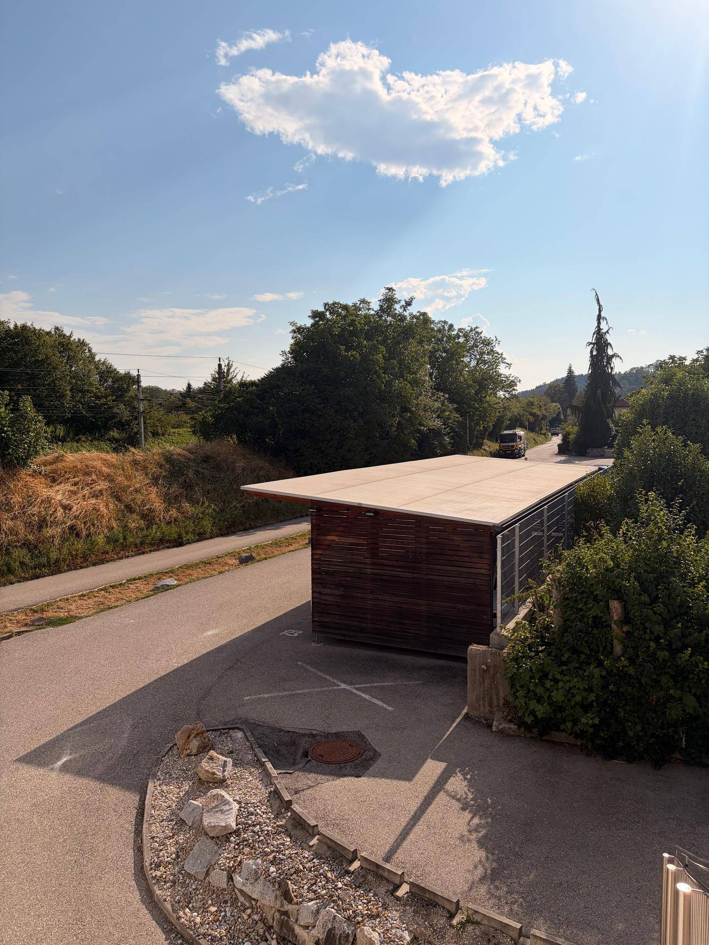 Außenansicht mit Carport und Zufahrt, umgeben von viel Grün und Natur.