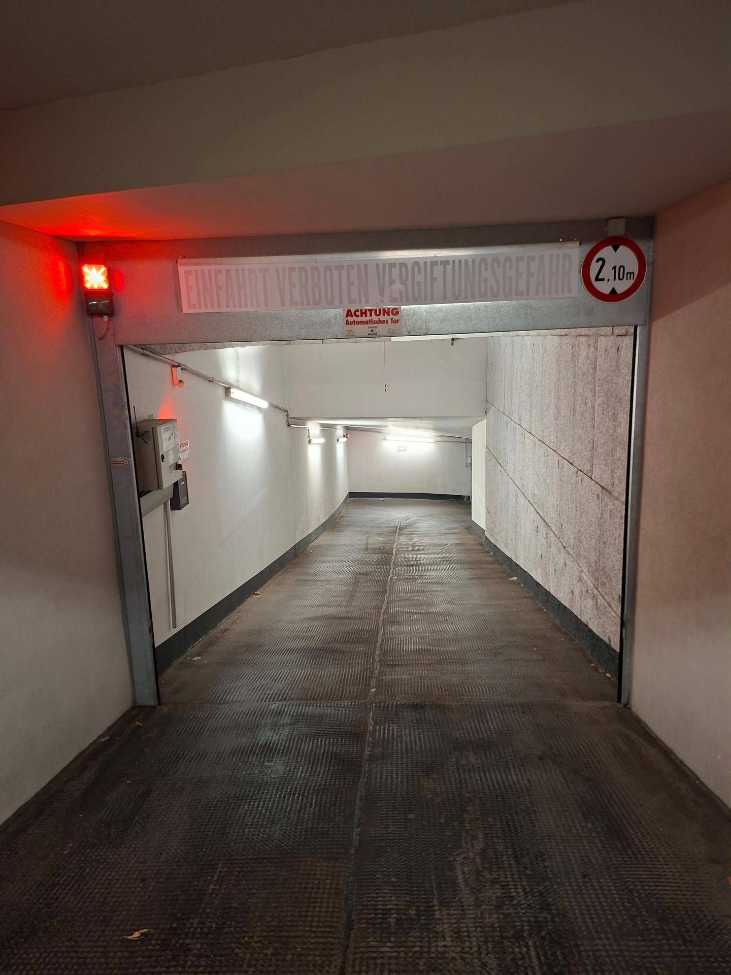 Eingangsbereich einer Tiefgarage mit Rampe, Warnleuchte und Verbotsschild.