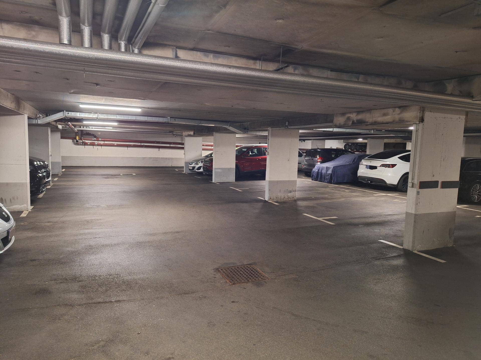 Geräumige Tiefgarage mit vielen Stellplätzen und verschiedenen geparkten Autos.