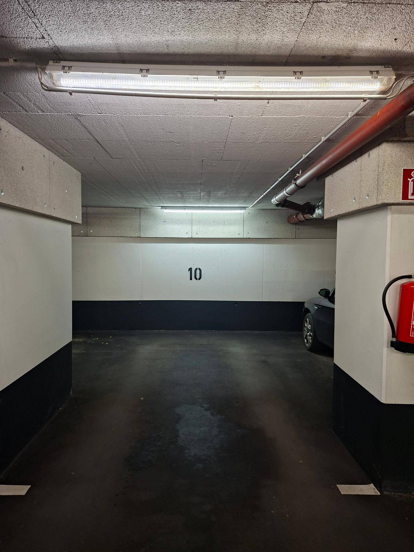 Tiefgaragenstellplatz Nummer 10 mit Betonpfeilern und Brandschutzvorrichtung.