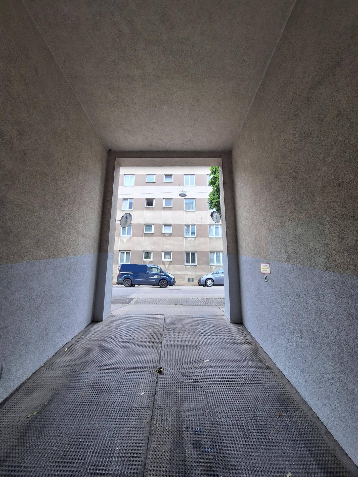 Garageneinfahrt mit Blick auf die Straße, ein Wohngebäude und geparkte Fahrzeuge.