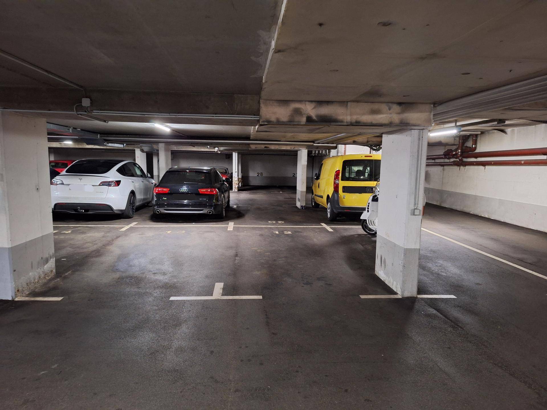 Tiefgarage mit mehreren geparkten Fahrzeugen und Betonstützen.