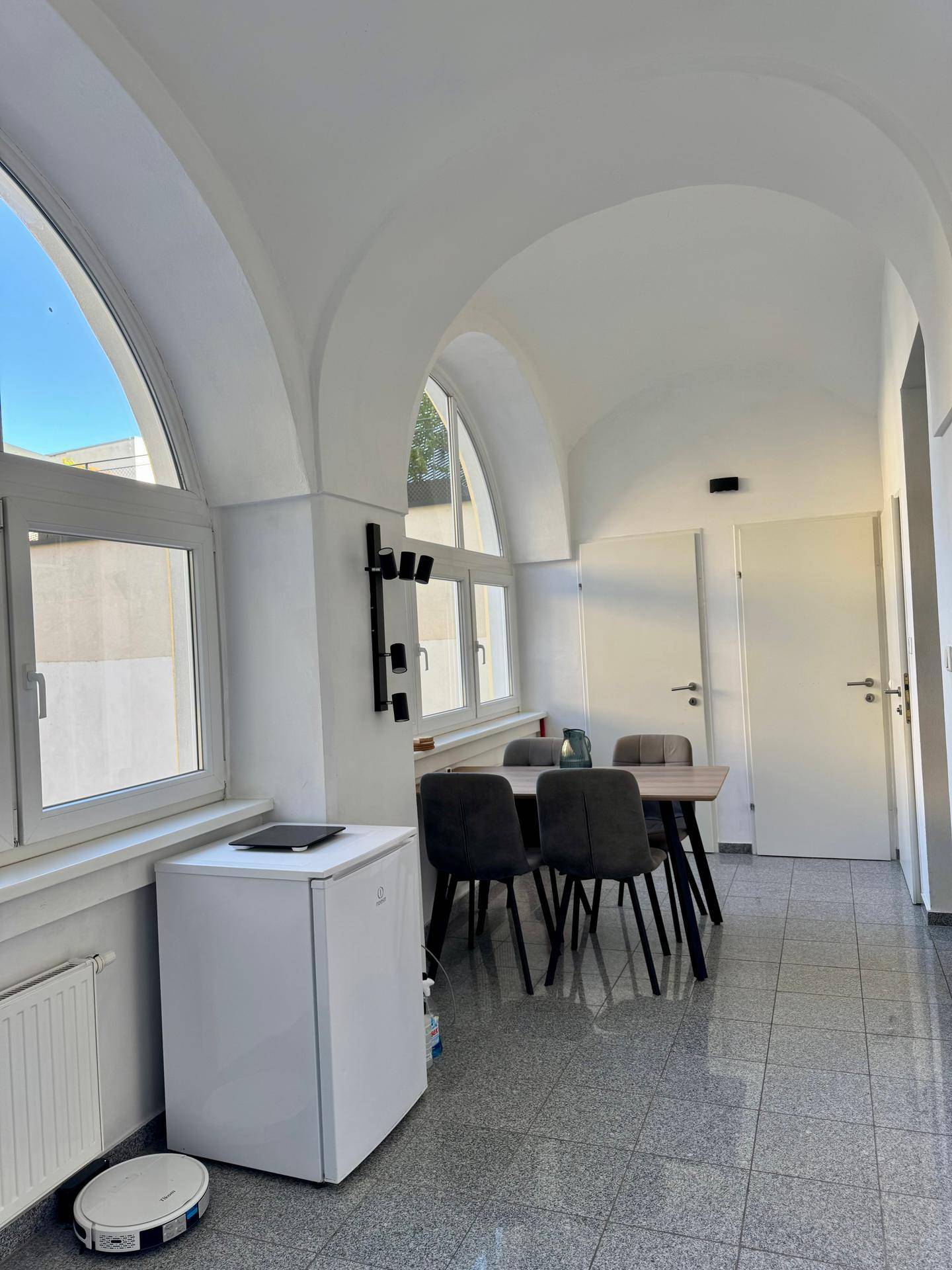 Heller Essbereich mit gewölbter Decke, großen Bogenfenstern und einem Esstisch mit Stühlen.