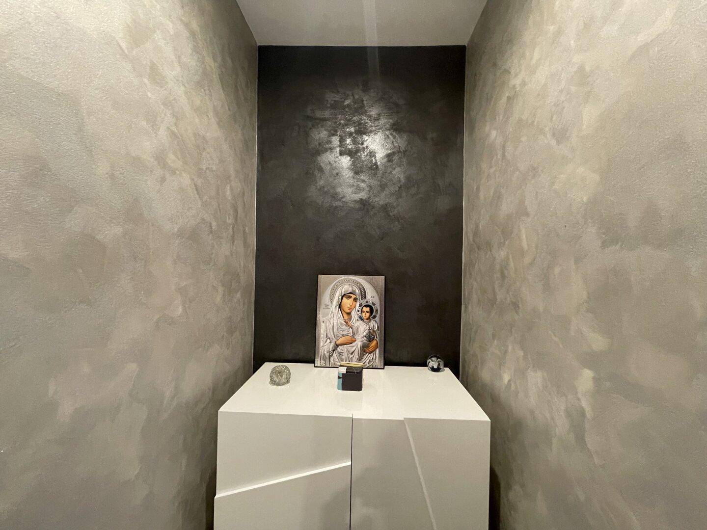 Dekorativer Nischenbereich mit Kunstwerk und modernem Schrank, beleuchtet von oben.