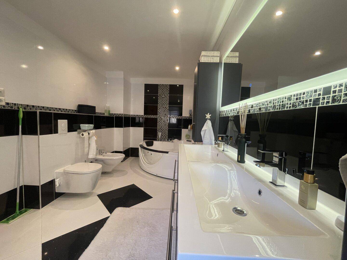 Luxuriöses Badezimmer mit schwarzen und weißen Fliesen, Doppelwaschbecken und Whirlpool-Badewanne.