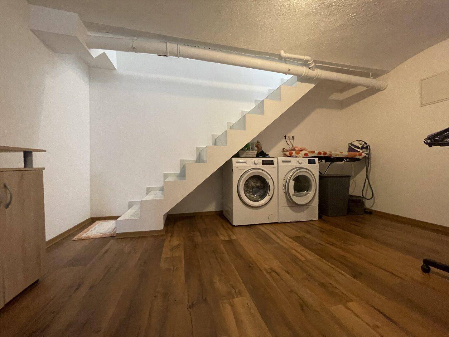 Praktischer Hauswirtschaftsraum mit Waschmaschinen und Trockner unter der Treppe.
