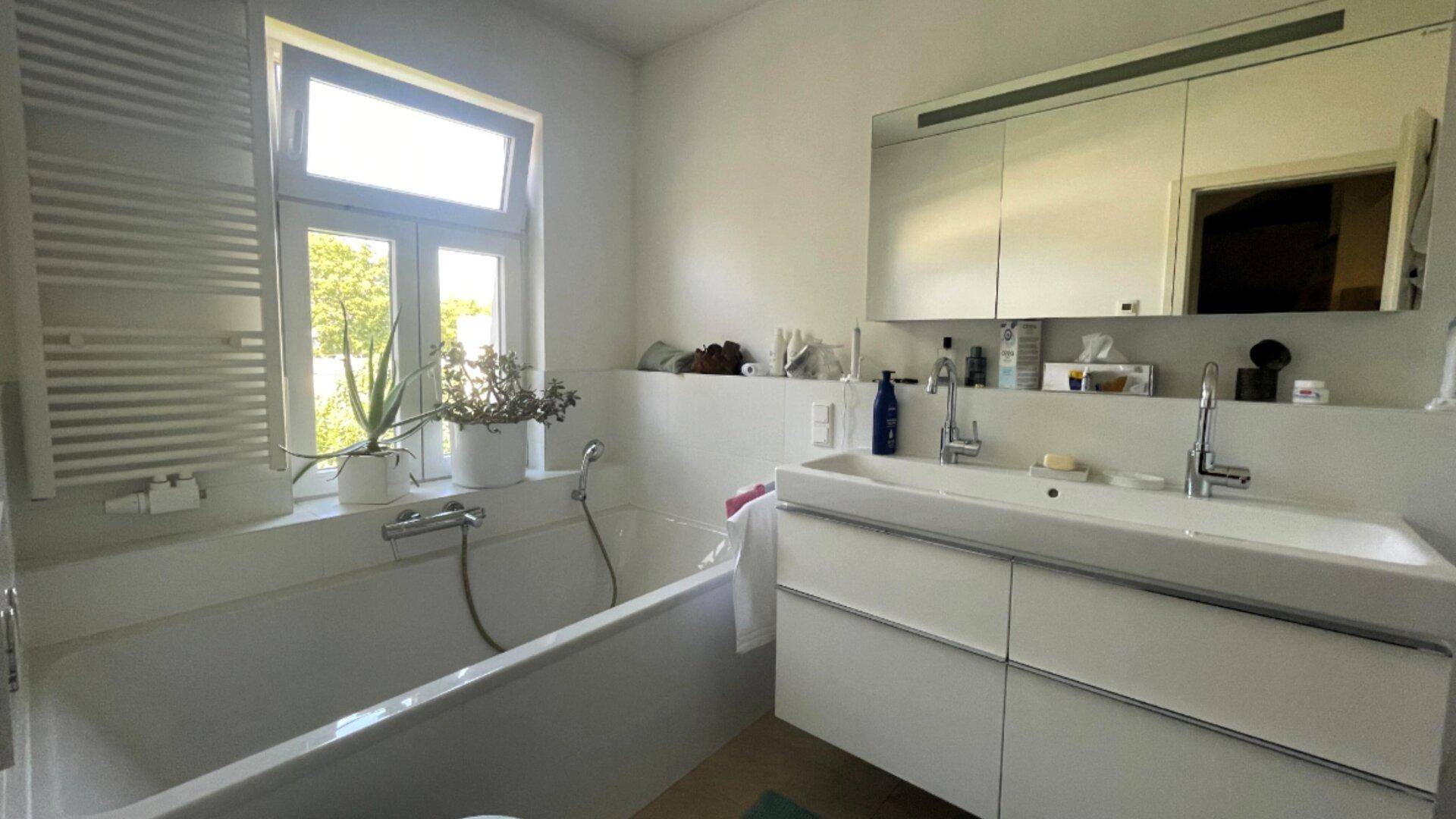 Modernes Badezimmer mit Badewanne, Einzelwaschbecken und Fenster für Tageslicht.