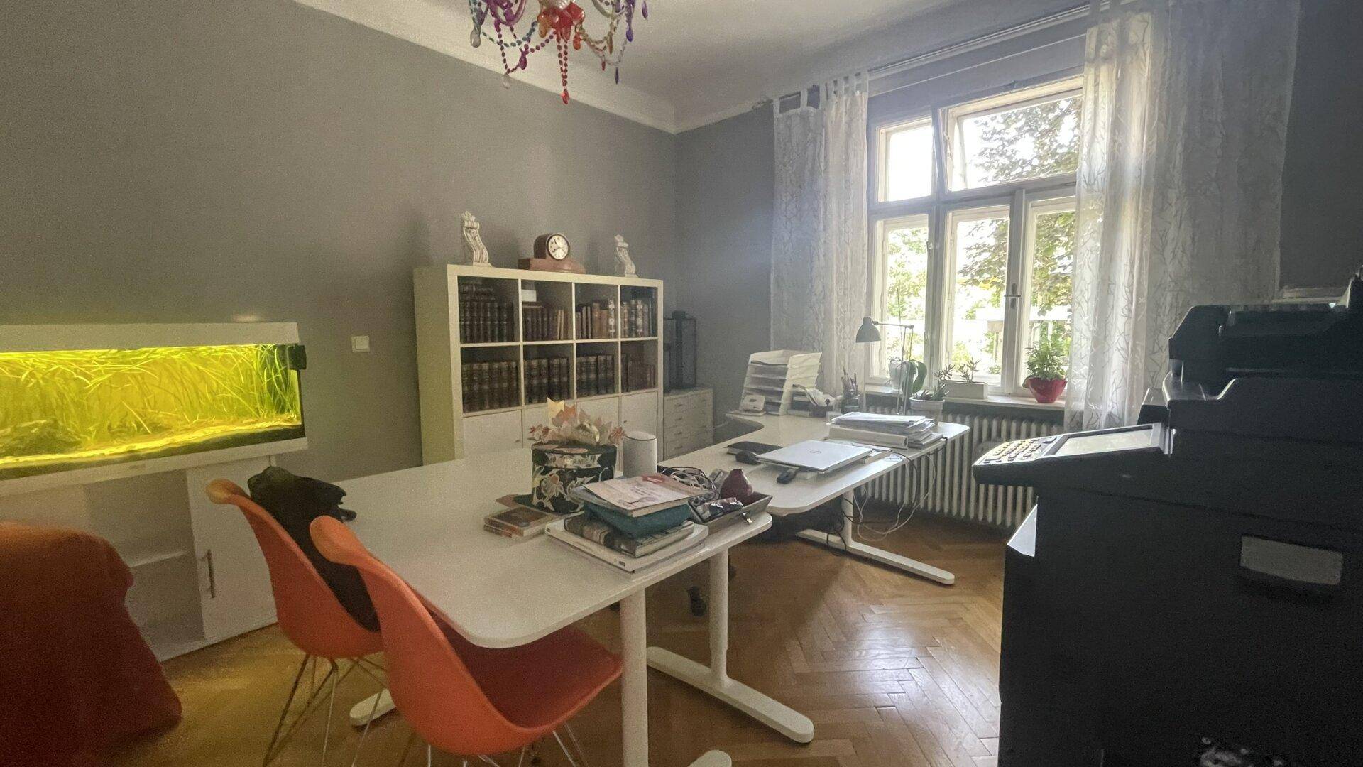 Geräumiges Arbeitszimmer mit Fischgrätparkett, großem Schreibtisch und Bücherregal.