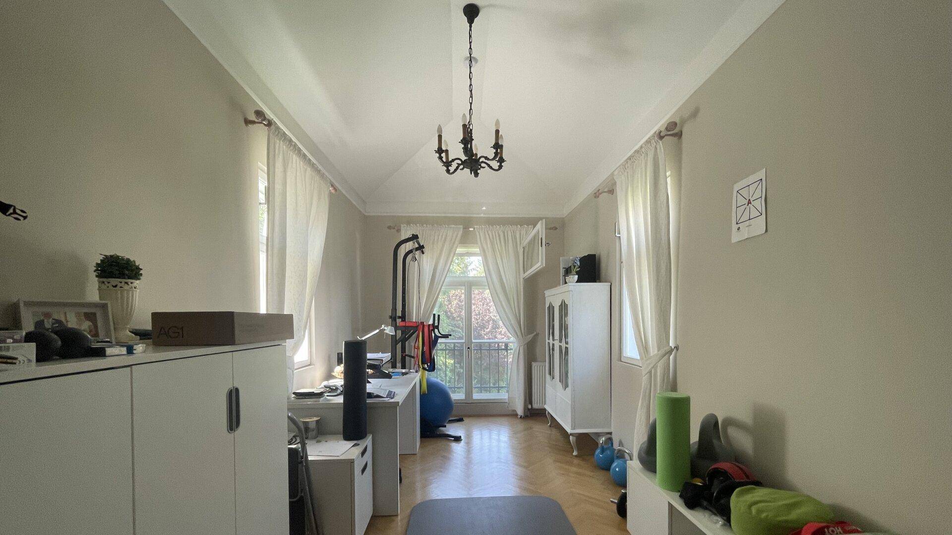 Vielseitiger Raum mit Fitnessgeräten, Schreibtisch und Zugang zu einem französischen Balkon.