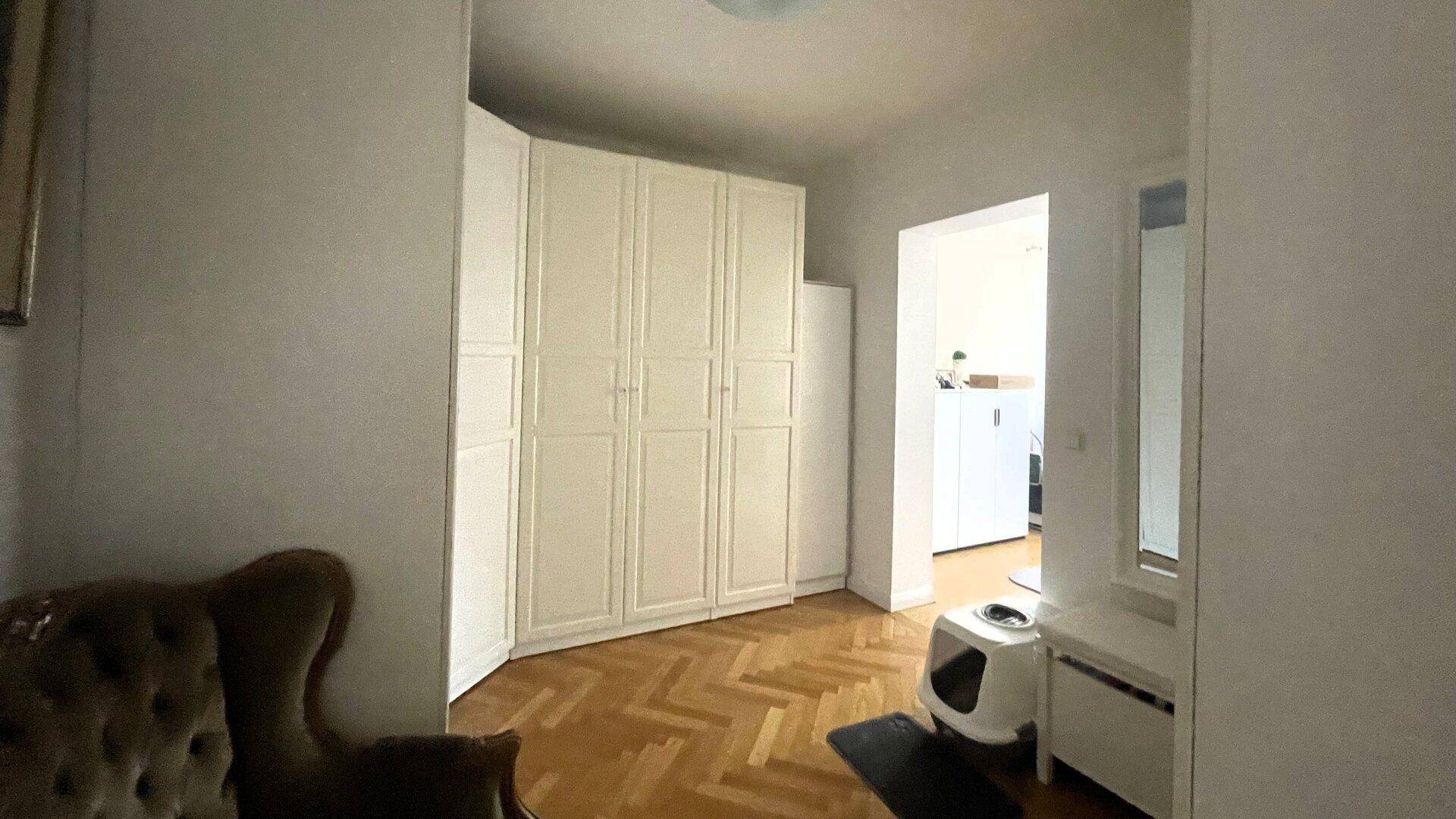 Heller Flur mit Einbauschränken und Fischgrätparkett, der zu weiteren Räumen führt.