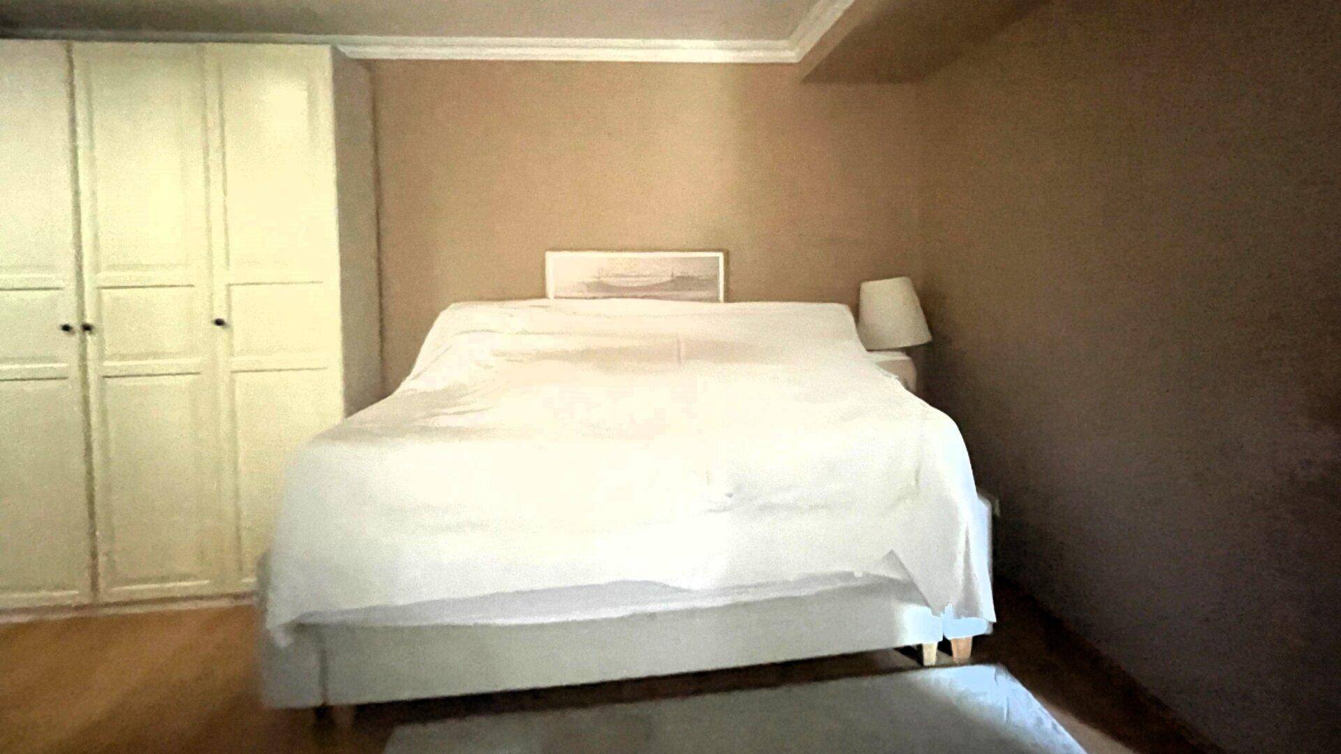 Schlafzimmer mit Doppelbett, Einbauschränken und warmen Brauntönen an den Wänden.