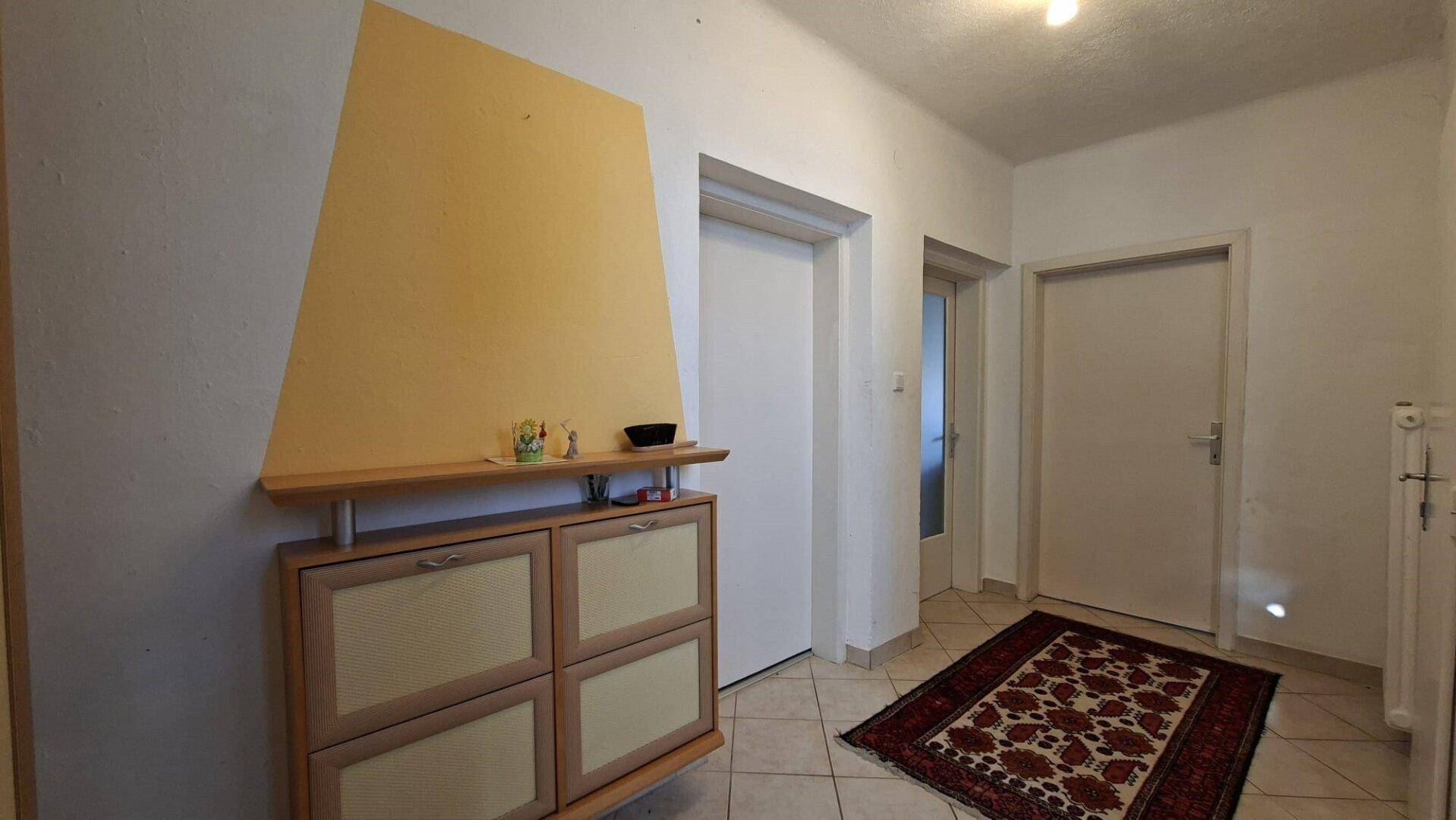Flur mit Schuhschrank, Fliesenboden und Zugang zu weiteren Räumen.