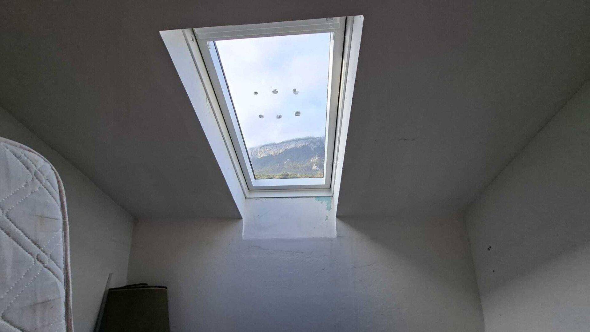 Dachzimmer mit Dachfenster und Blick auf die umliegenden Berge.