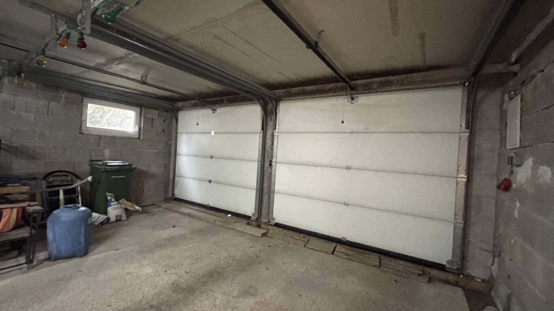 Geräumige Doppelgarage mit zwei Sektionaltoren und einem Fenster für Tageslicht.