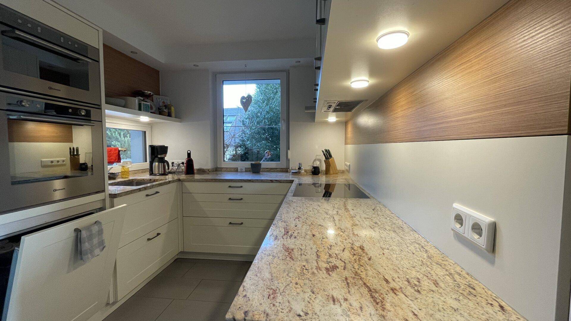 Moderne Küche mit hellen Schränken, Granitarbeitsplatten und integrierten Geräten, mit Fenster.