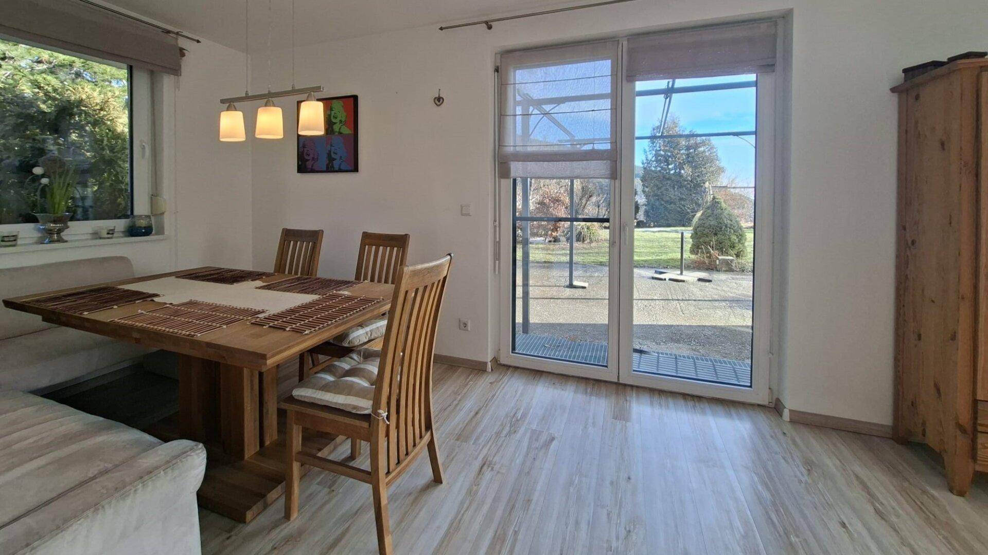 Essbereich mit Holztisch und Stühlen, Zugang zur Terrasse und Blick in den Garten.