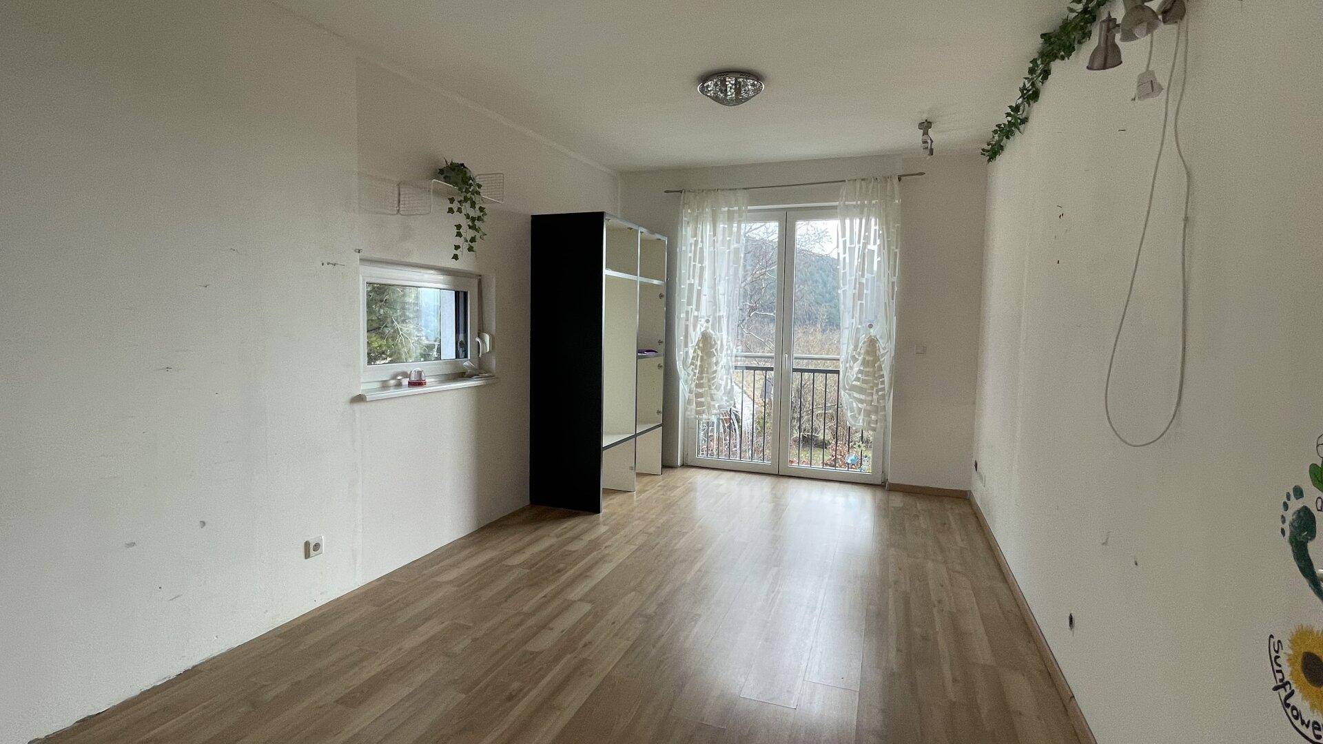 Geräumiges Schlafzimmer mit Laminatboden und Zugang zu einem französischen Balkon.