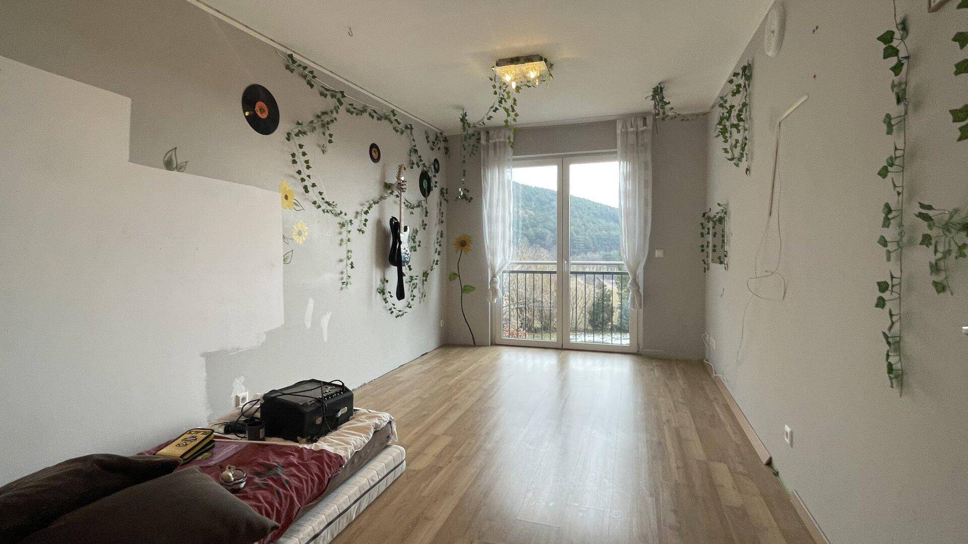 Schlafzimmer mit Laminatboden und Zugang zu einem französischen Balkon, individuell gestaltet.