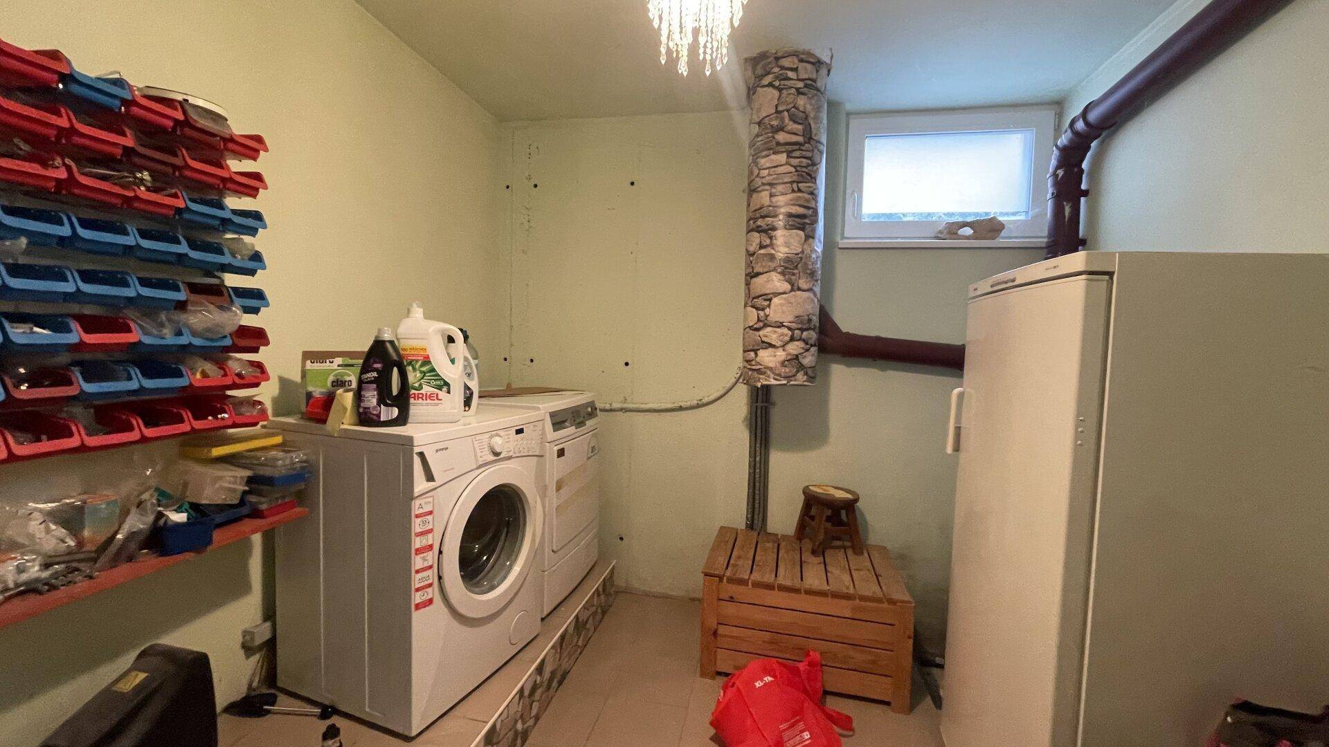 Praktischer Hauswirtschaftsraum im Keller mit Waschmaschine, Trockner, Gefrierschrank und Regalen für Lagerung.