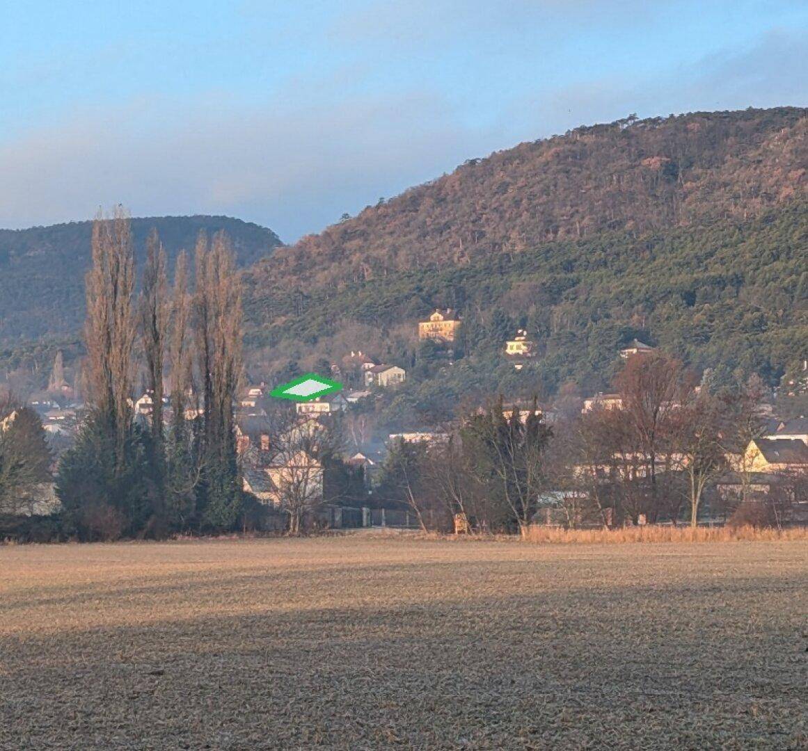 Malerischer Fernblick auf ein Dorf in einer Talmulde, umgeben von bewaldeten Hügeln.