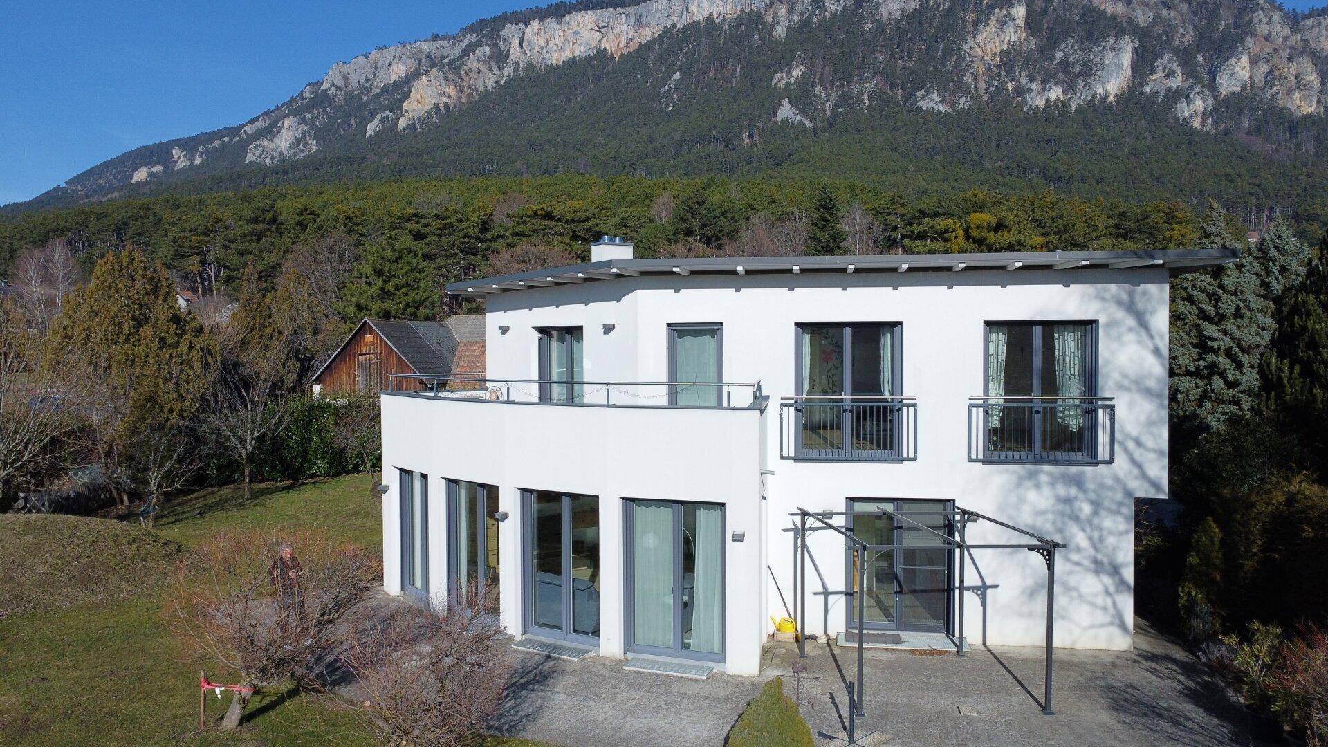 Ansicht des modernen Wohnhauses mit weißer Fassade, Balkonen und einer überdachten Terrasse.
