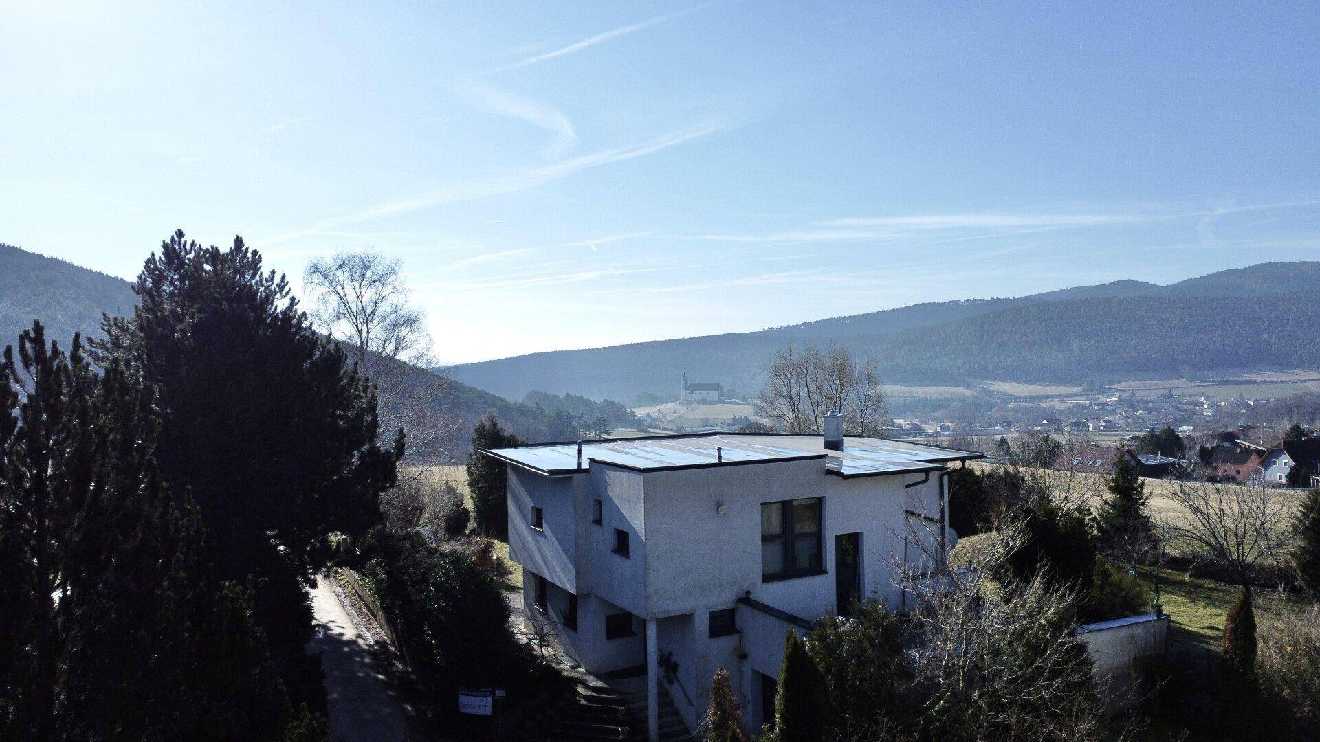 Seitenansicht des Hauses in ländlicher Umgebung mit weitem Blick auf die hügelige Landschaft.