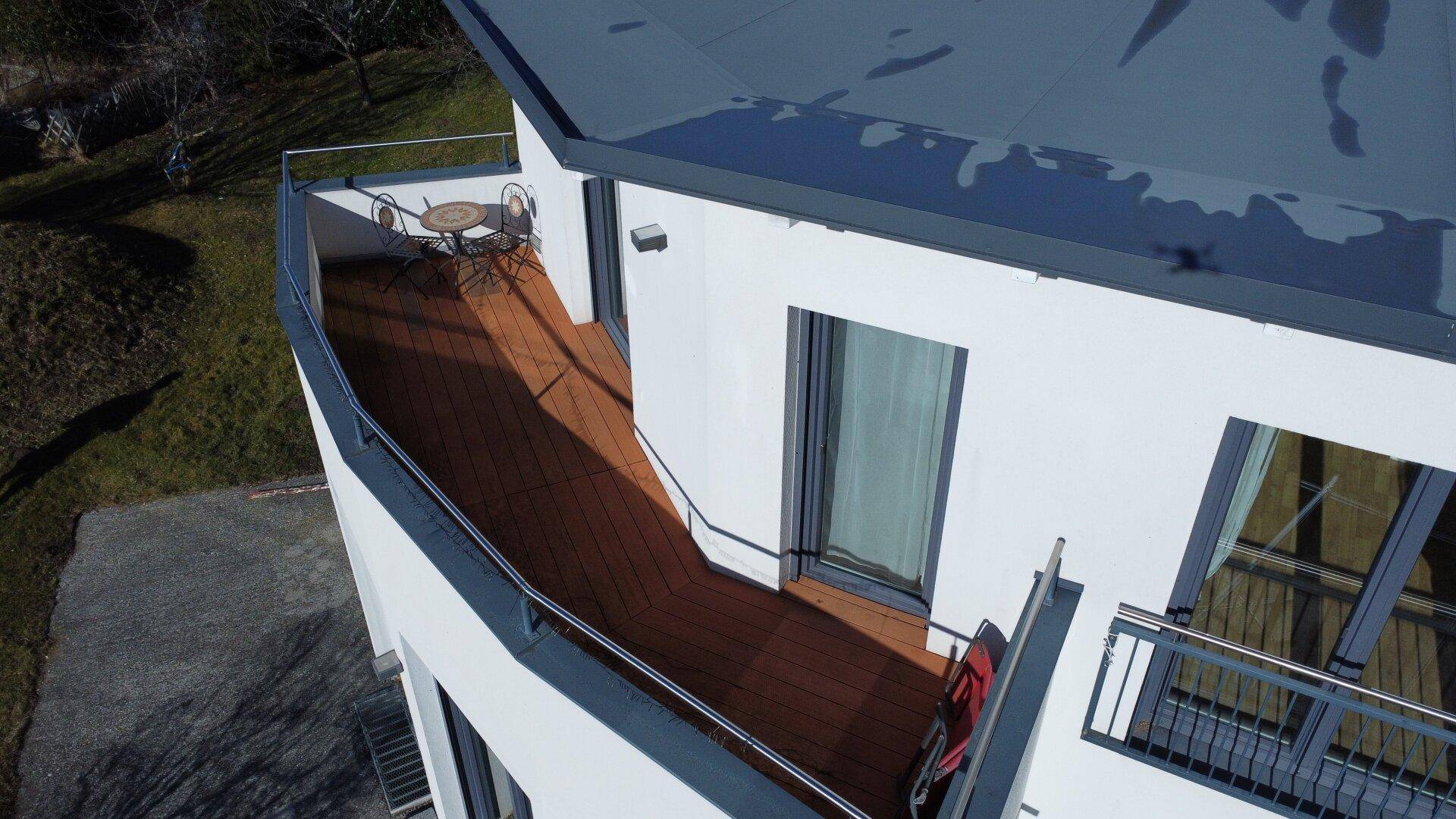 Großer Balkon mit Holzboden und Metallgeländer, ideal für entspannte Stunden im Freien.
