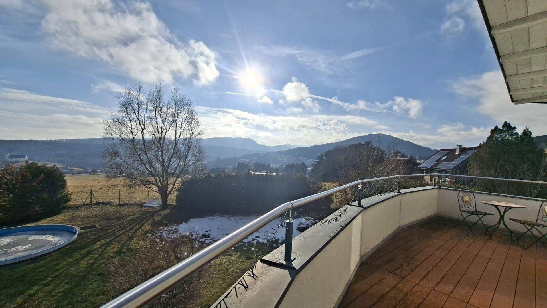 Sonniger Balkon mit weitem Blick auf die umliegende Berglandschaft und den Garten.