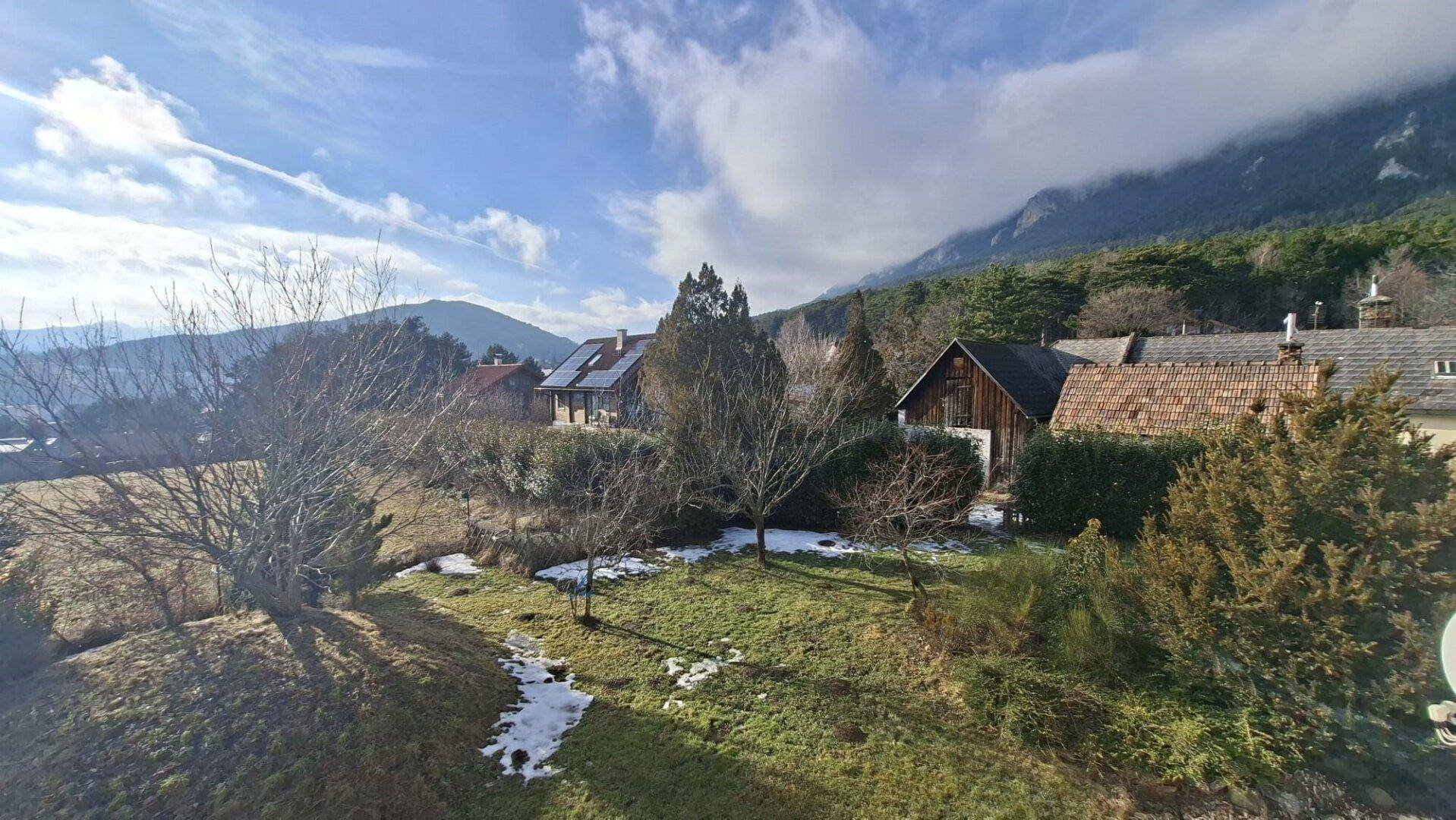 Weitläufiger Blick auf die Nachbarschaft mit mehreren Häusern, Bäumen und Bergen im Hintergrund.