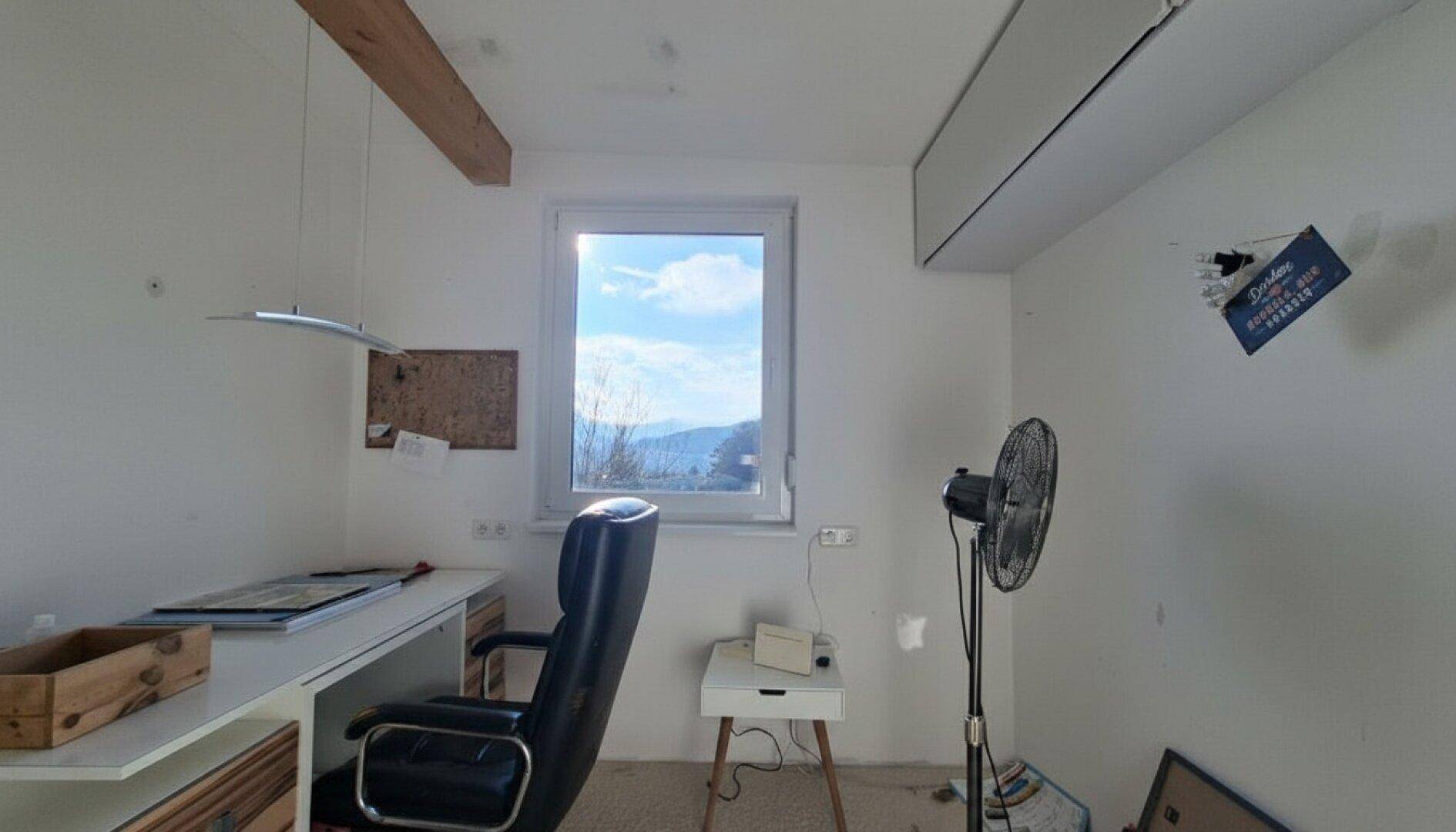 Helles Arbeitszimmer mit Schreibtisch und Fenster, das einen weiten Blick bietet.