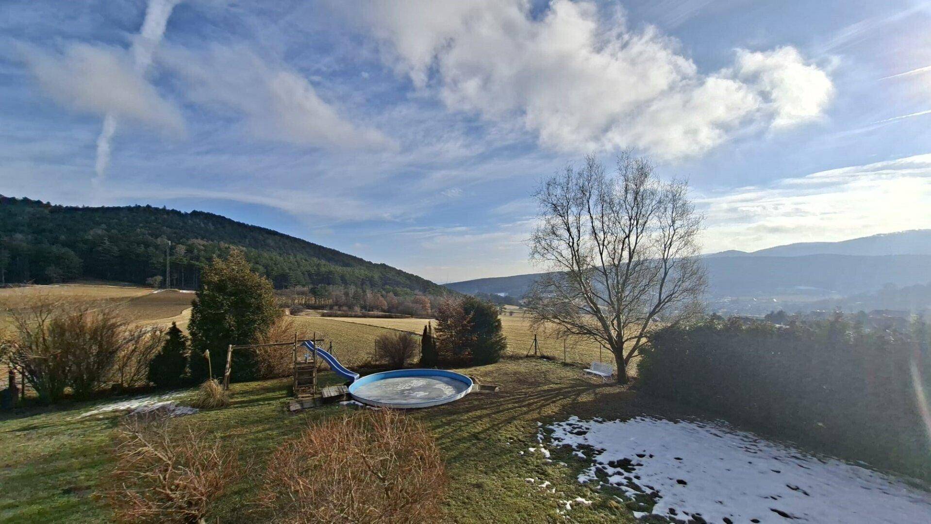 Weitläufiger Gartenbereich mit kleinem Pool, Schaukel und weitem Blick auf die umliegende Hügellandschaft.
