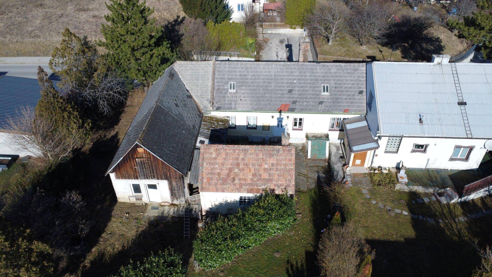 Vogelperspektive des Grundstücks mit Wohnhaus, Nebengebäuden und Gartenbereich.