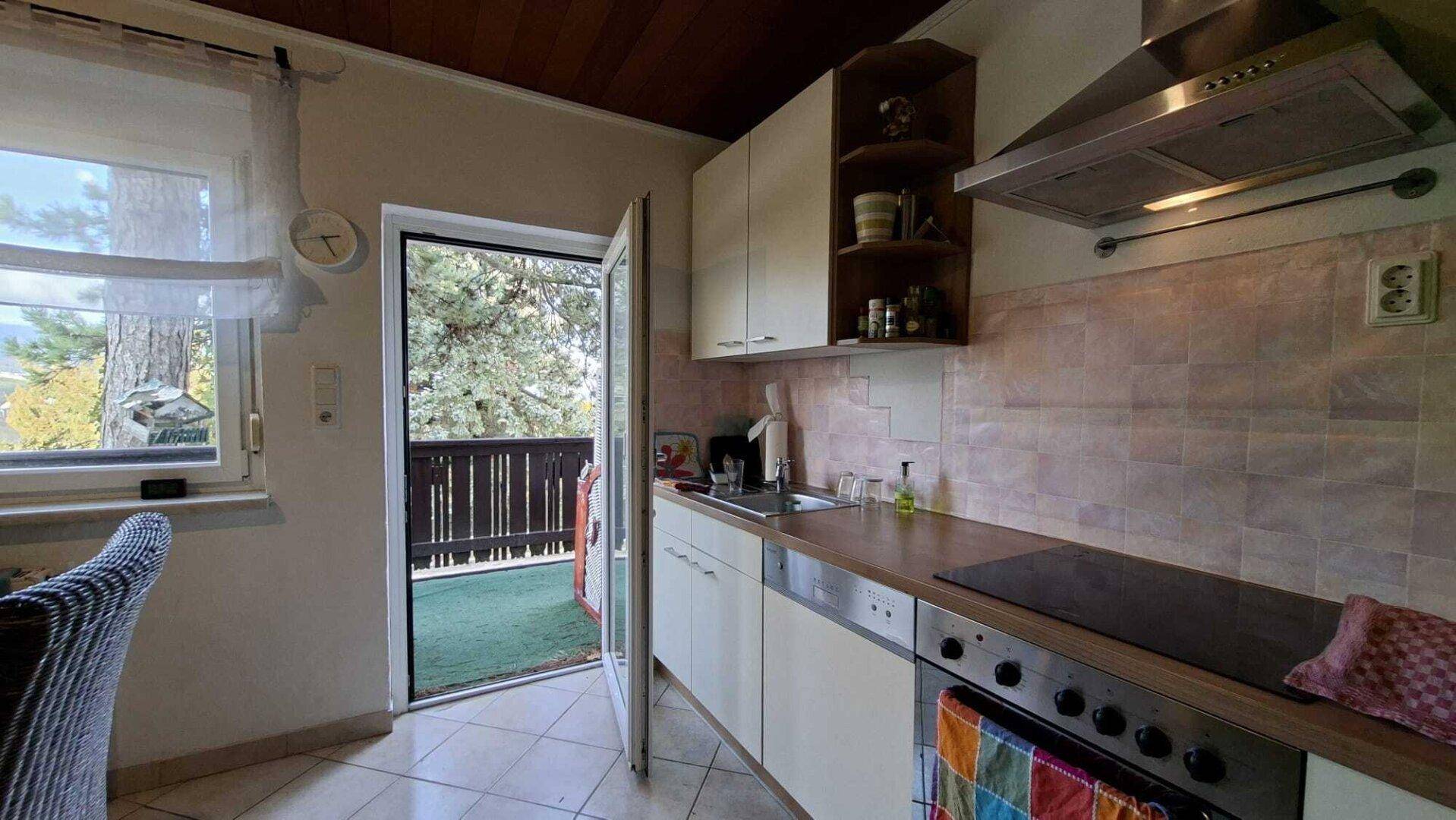 Küche mit Einbaugeräten, Holzdecke und Zugang zu einem kleinen Balkon.