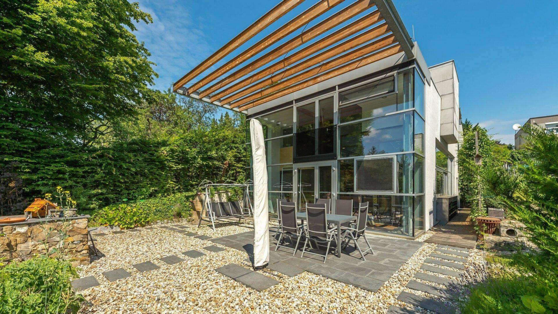 Geräumige Terrasse mit Sitzgelegenheiten und Kiesflächen, umgeben von üppigem Grün.