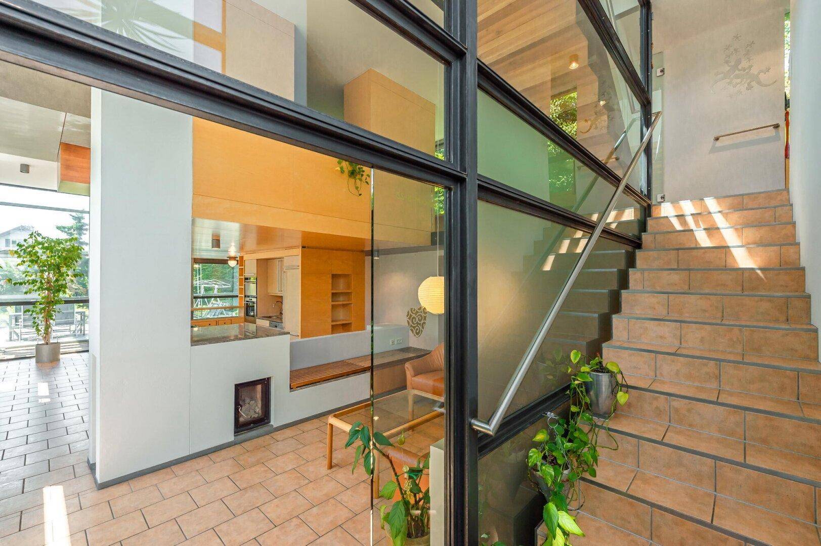 Heller Eingangsbereich mit moderner Treppe aus Holz und Glas, die die Etagen verbindet.