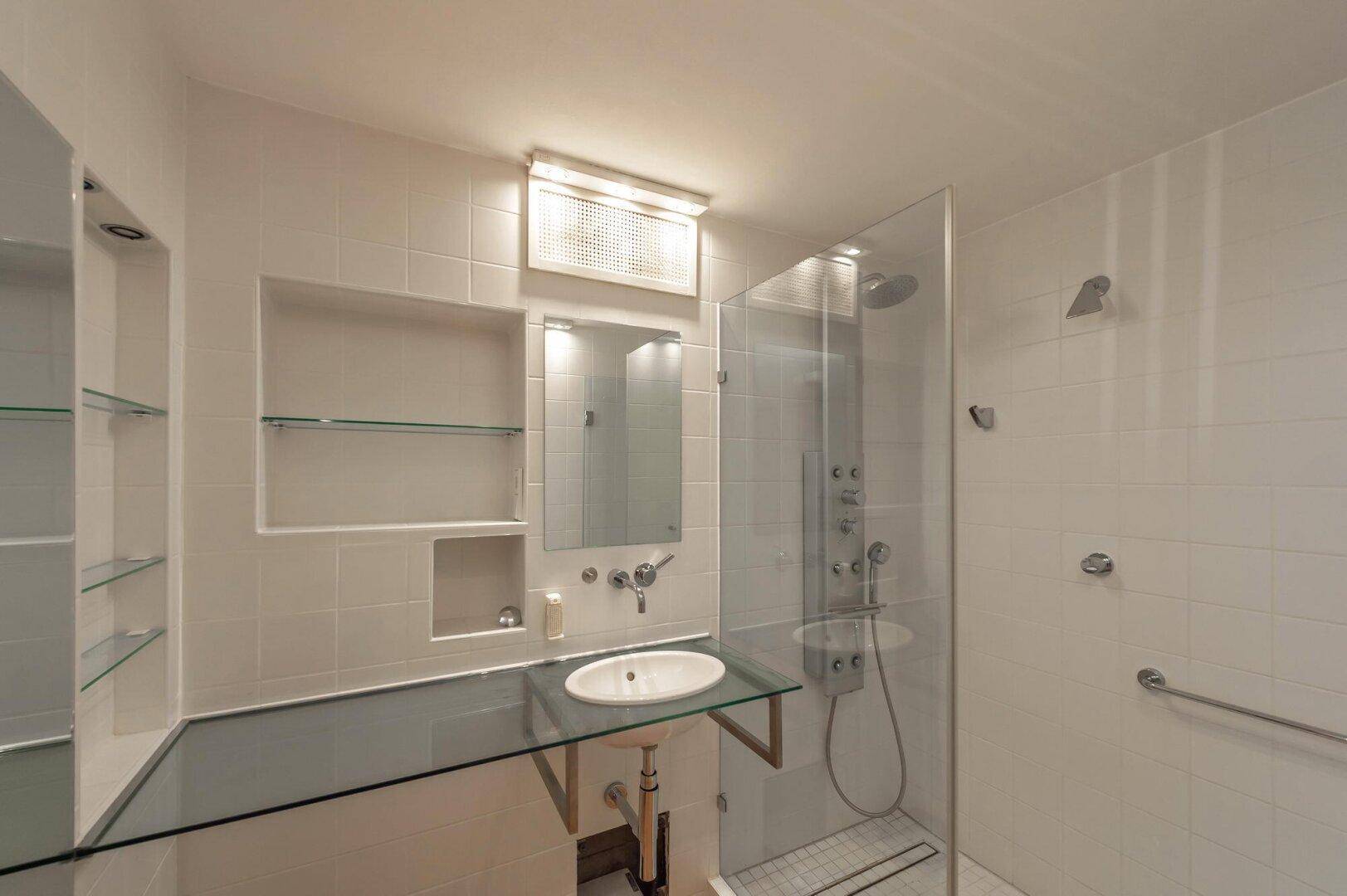 Modernes Badezimmer mit Duschkabine, Einzelwaschbecken und weißen Fliesen.