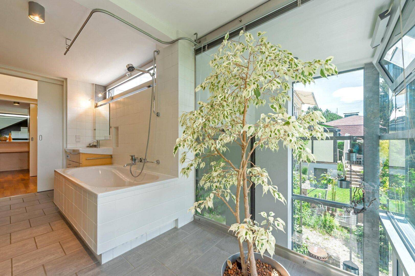 Helles Badezimmer mit Badewanne und raumhohen Fenstern, die viel Licht hereinlassen.