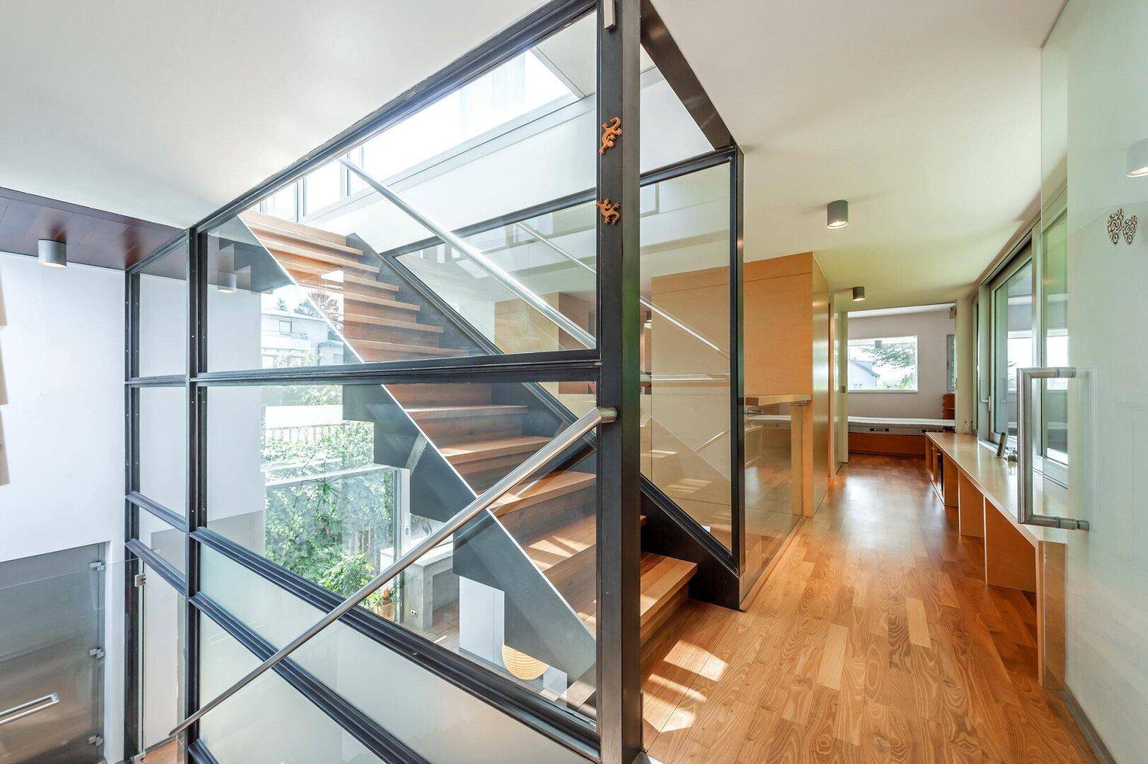 Moderne Treppe mit Glasgeländer und Holzstufen, die die verschiedenen Ebenen verbindet.