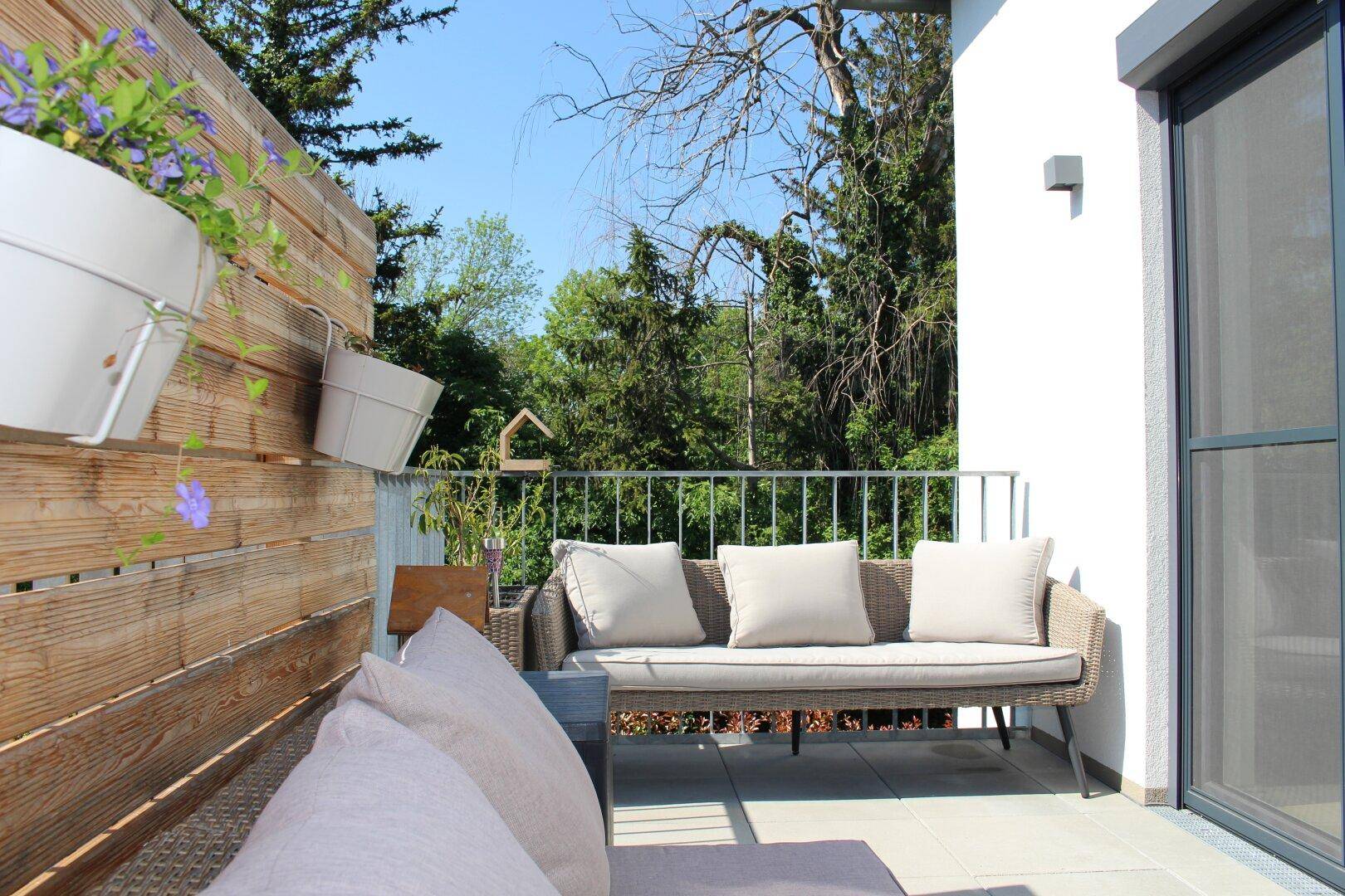 Sonniger Balkon mit bequemen Sitzmöbeln und weitem Blick ins Grüne, ideal für entspannte Stunden.