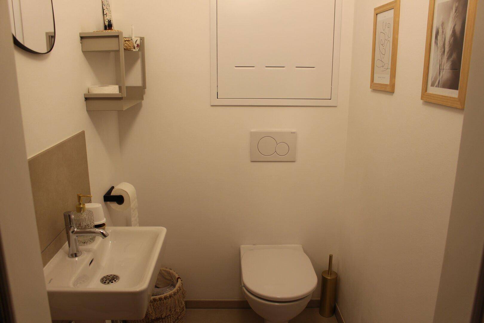 Kleines Gäste-WC mit Wand-WC und modernem Waschbecken, funktional und platzsparend.