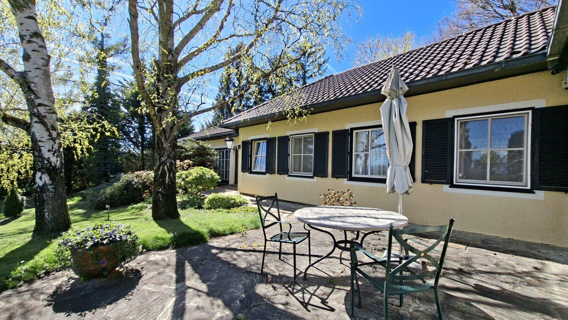 Gemütliche Terrasse am Haus mit Gartenmöbeln und Blick ins Grüne an einem sonnigen Tag.