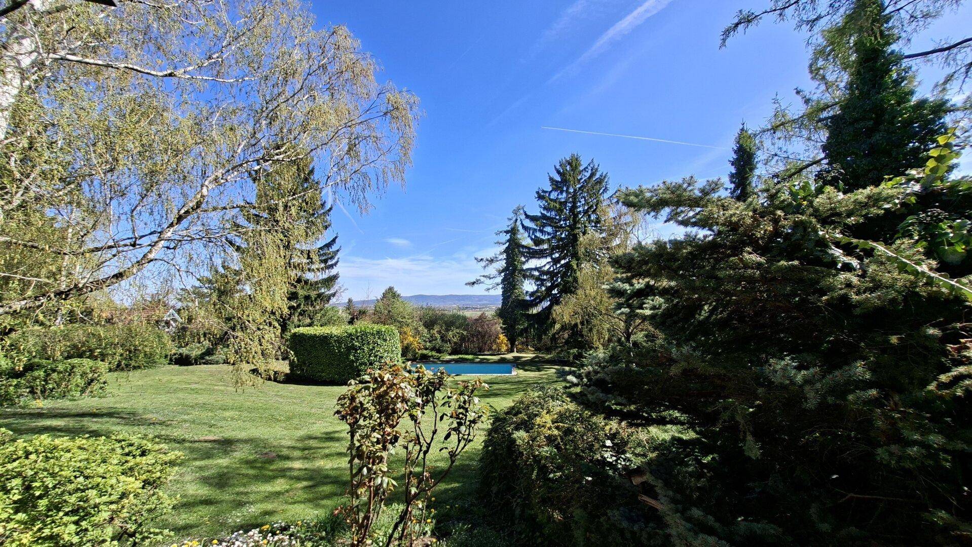Weitläufiger Garten mit üppiger Bepflanzung, Pool und Fernblick in die Landschaft.