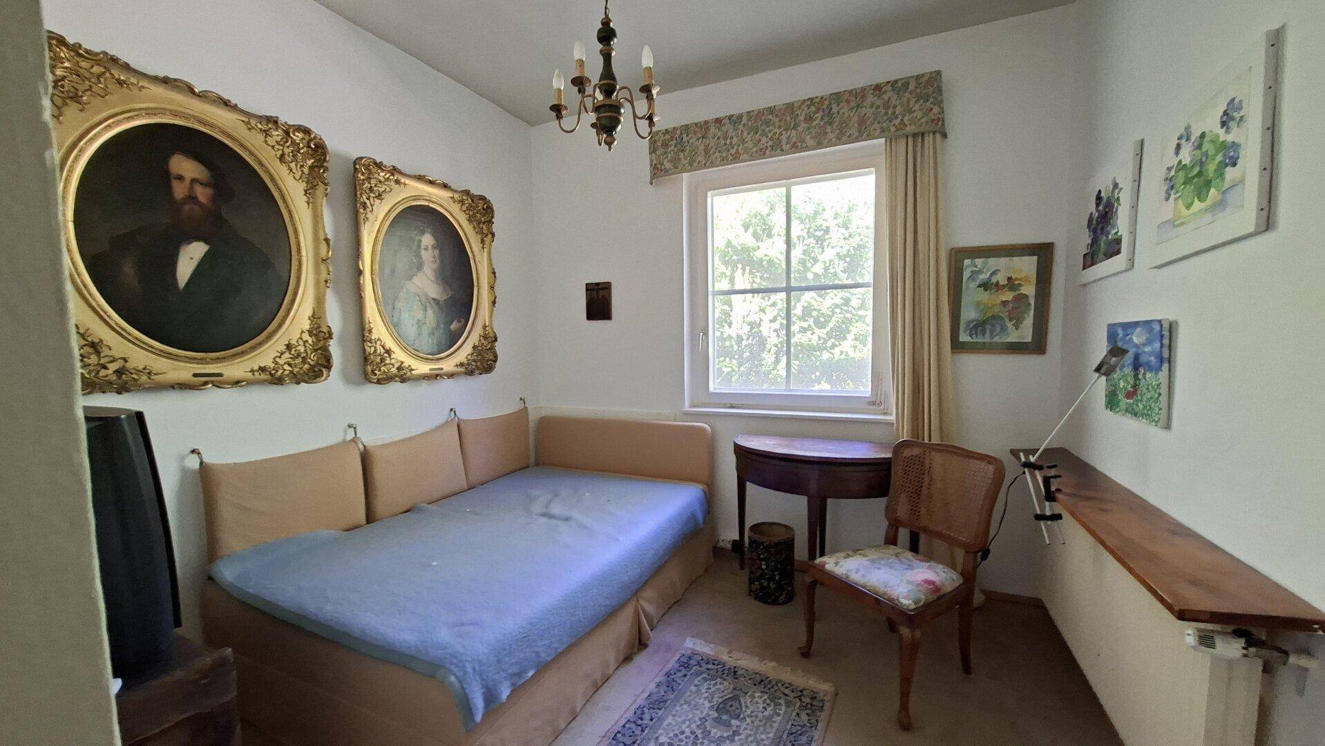 Gemütliches Schlafzimmer mit Einzelbett, klassischem Mobiliar und Kunstwerken an den Wänden.