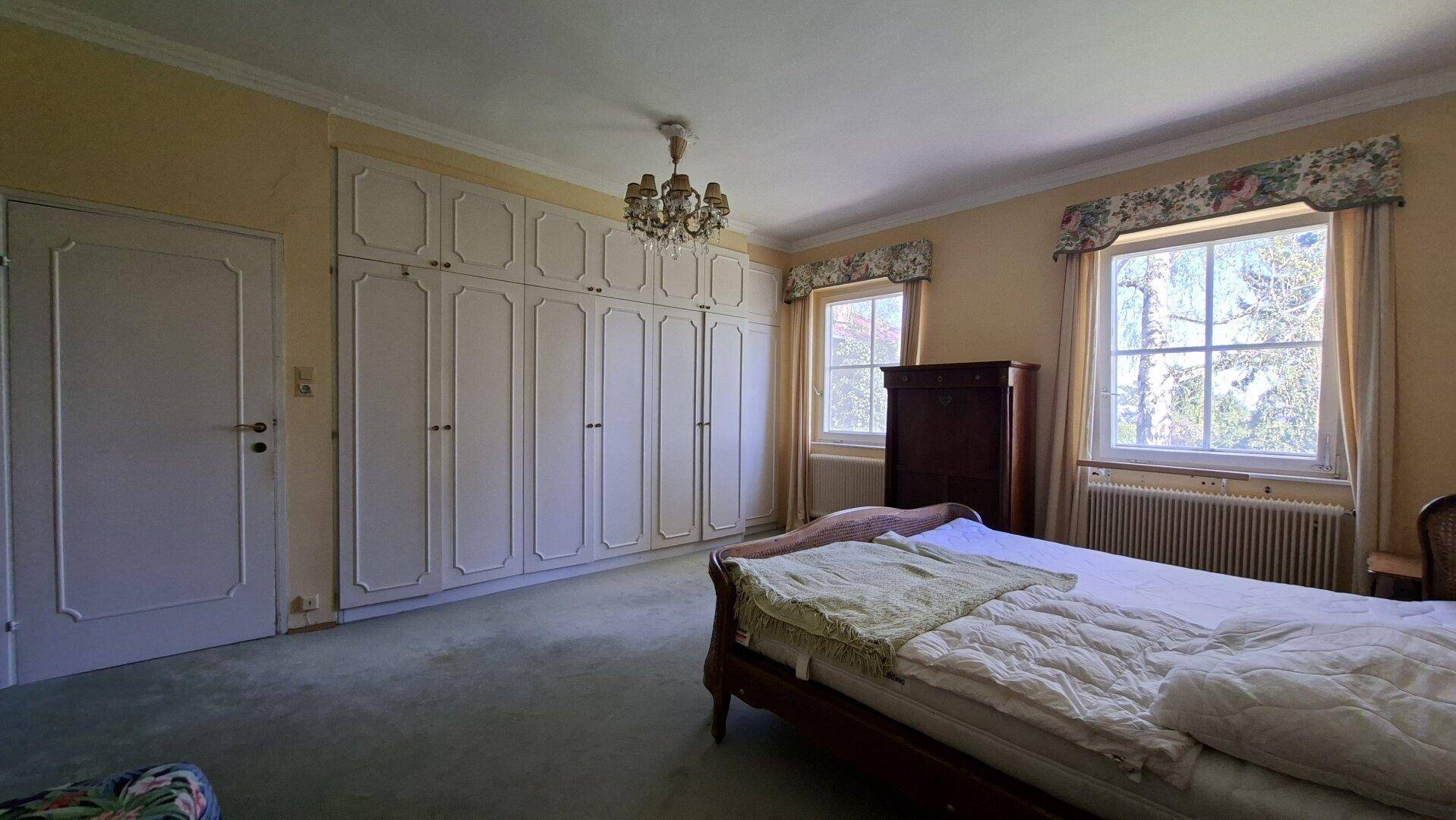 Geräumiges Schlafzimmer mit großem Einbauschrank, Doppelbett und grünem Teppichboden.